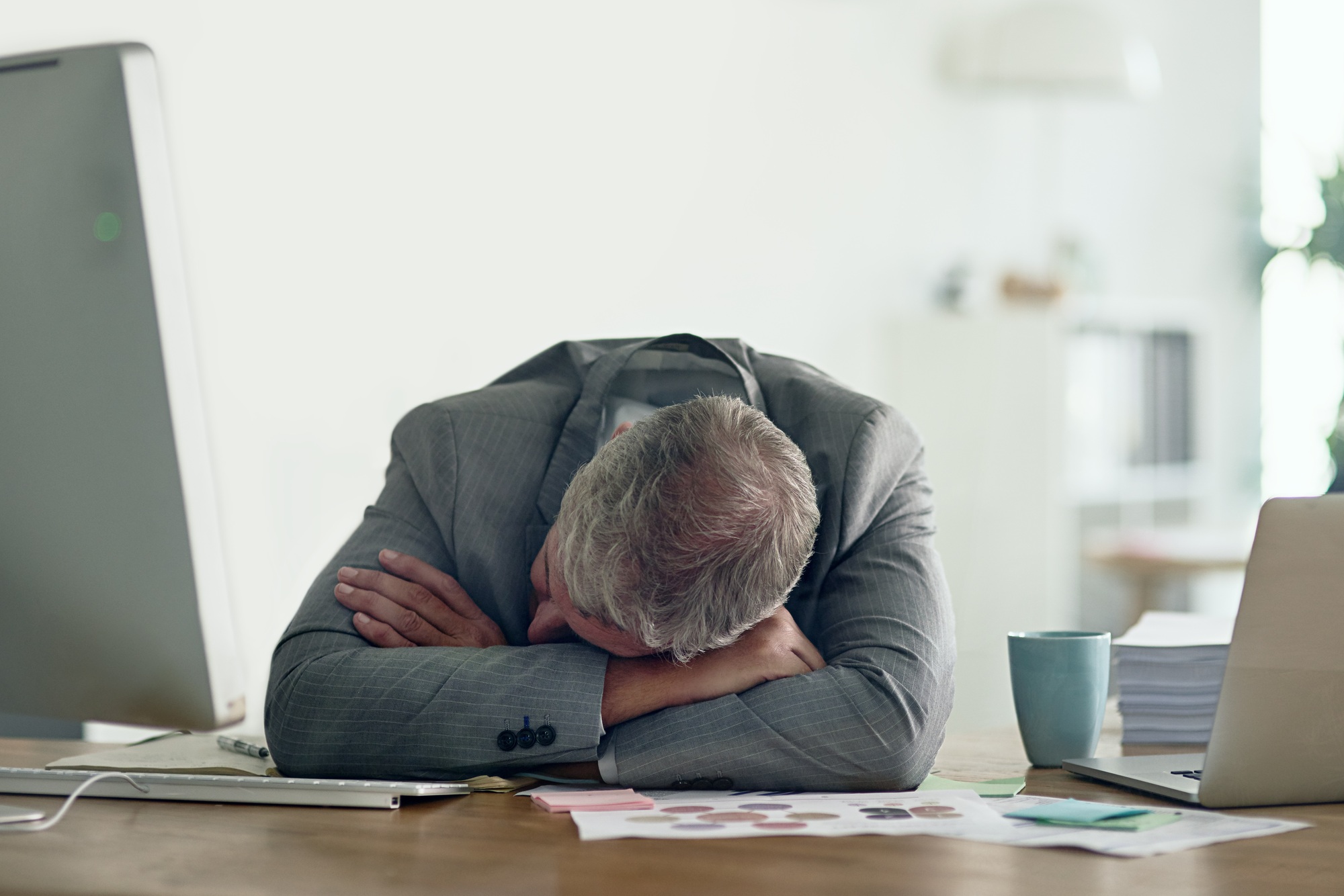 Shot of an exhausted businessman resting on his arms at his desk